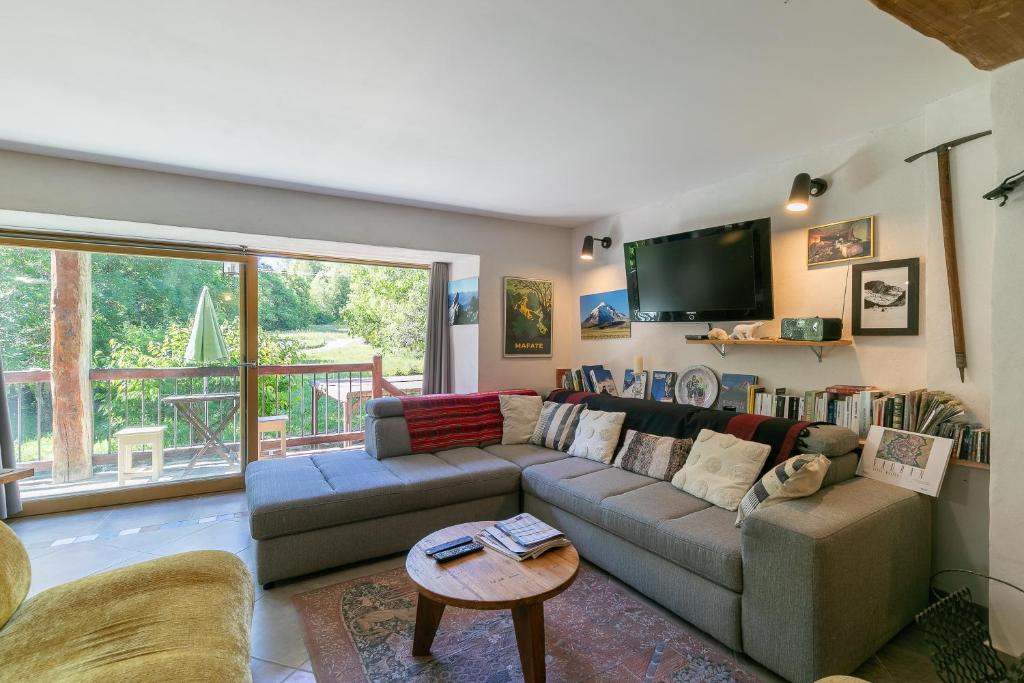 a living room with a couch and a tv at Les Rochas - Duplex pour 7 personnes in Champcella