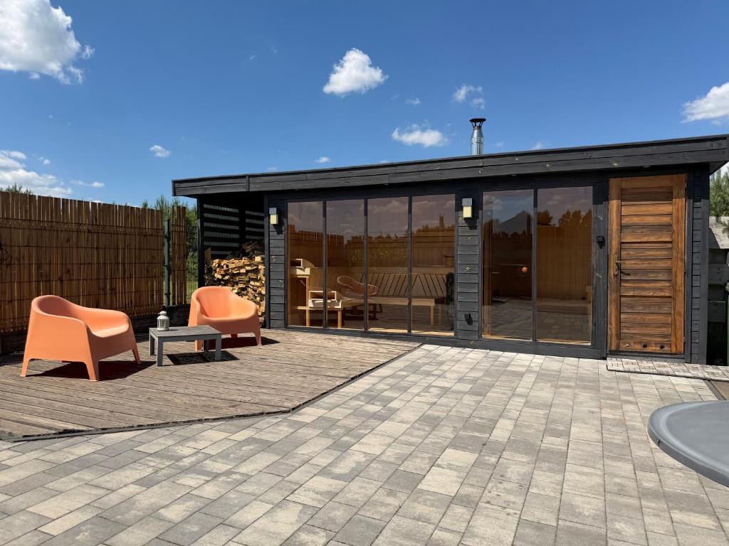 a house with glass doors and orange chairs on a patio at Wrzosowisko Sominy in Sominy