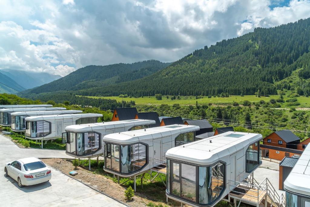 a row of campervs in a parking lot with a car at Capsule & Enesai Hotels Karakol in Karakol