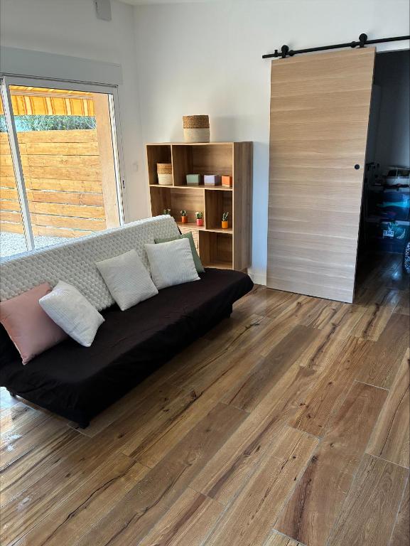 a living room with a couch and a wooden floor at chez ophélia in Sainte-Tulle