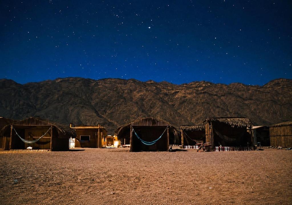 a group of huts in the desert at night at La Basha Camp in Dahab
