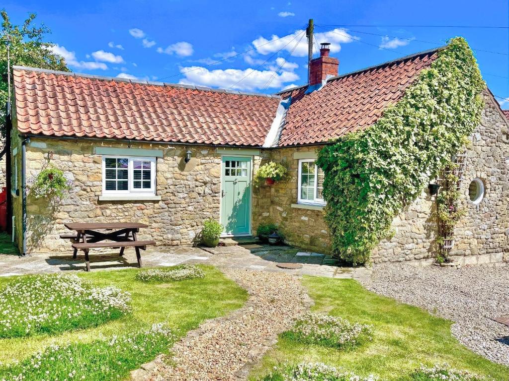 a stone cottage with a picnic table in front of it at Craven Bungalow in Allerston