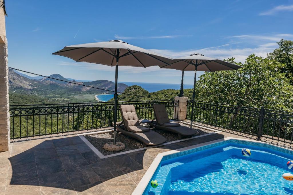 a swimming pool with an umbrella and a chair at Villa Robinson in Petrovac na Moru