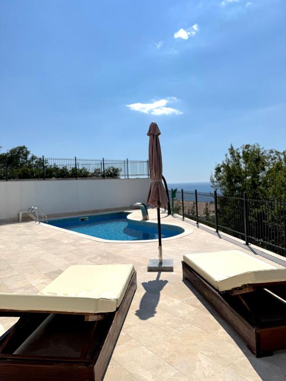 a patio with an umbrella and a swimming pool at Sea View Residence with Pool & Private Terrace in Krstac