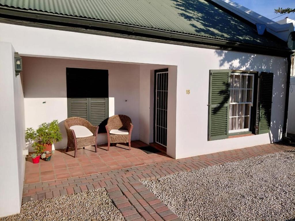 a patio with two chairs and a window at Springbok Cottage in Graaff-Reinet