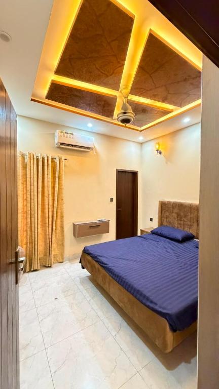 a bedroom with a bed with a blue comforter and a ceiling at Complete Comfy House with 3 beds Al-Hafeez Garden Lahore in Lahore