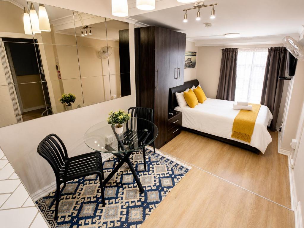 a bedroom with a bed and a glass table and chairs at Faith, Hope & Love Self Catering in Port Elizabeth