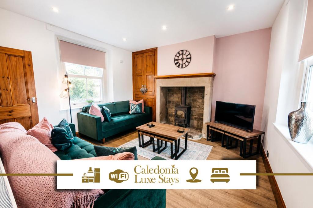 a living room with a green couch and a fireplace at Peak Cottage in Matlock