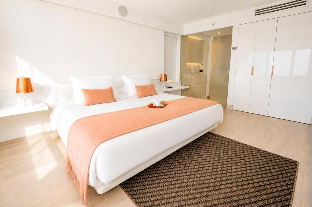 a white bedroom with a large bed and a bathroom at 45 by Director in Santiago