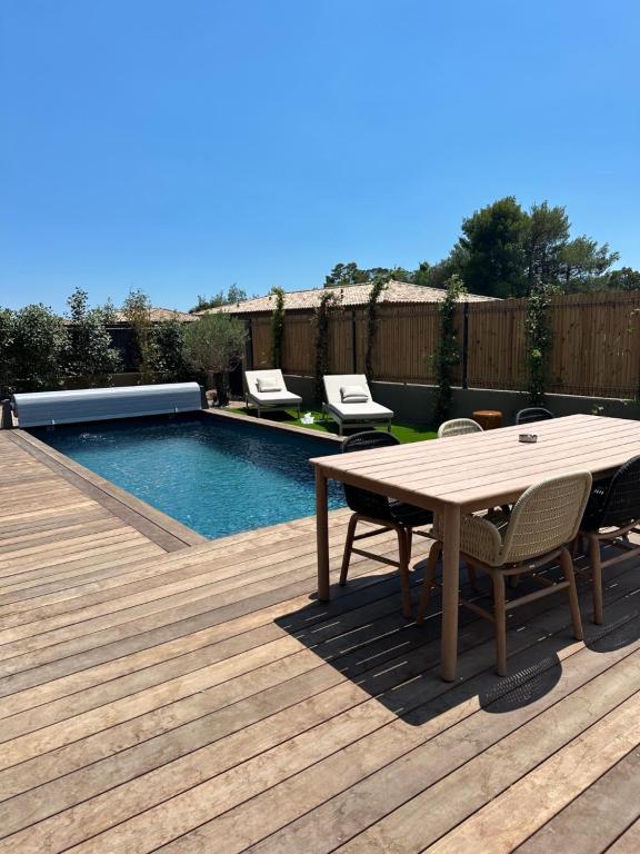 a wooden deck with a table and chairs next to a pool at Villas Vangarone in Lecci