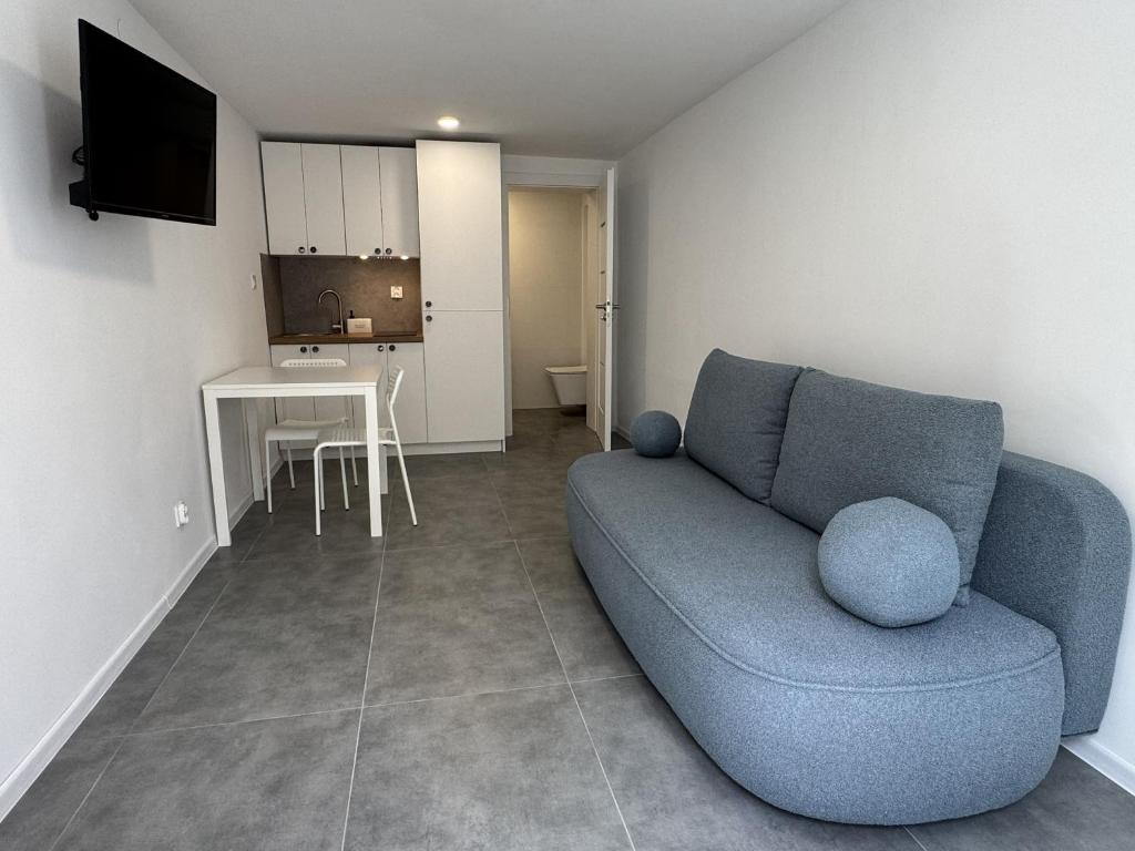 a living room with a blue couch and a kitchen at Piankowe mini-apart in Rewal