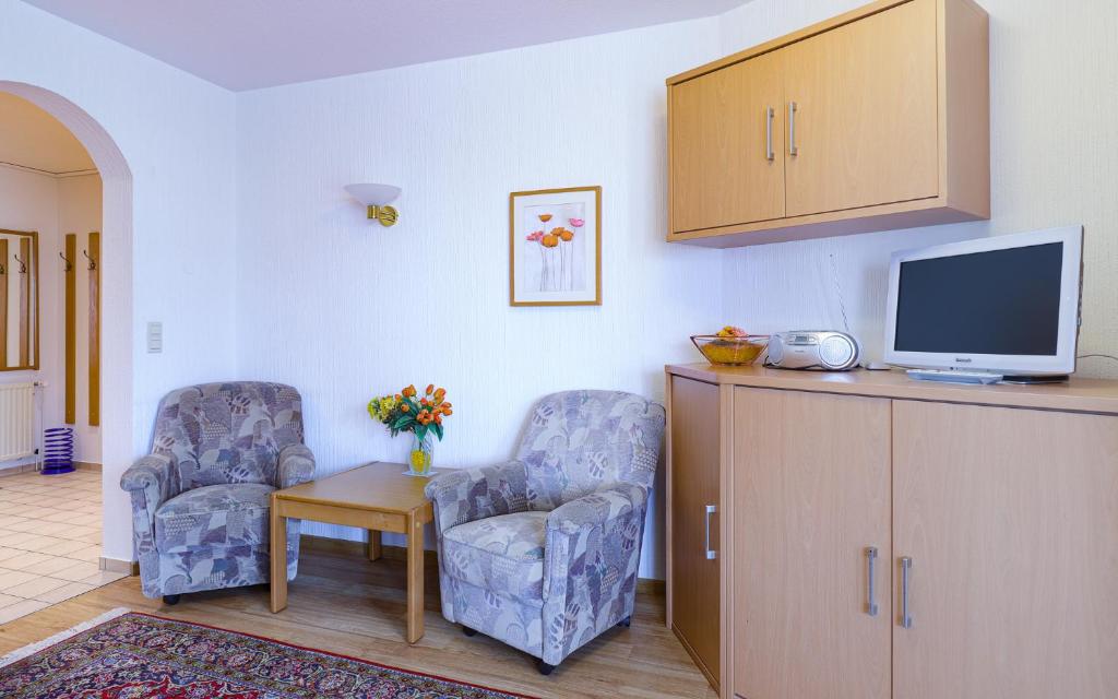 a living room with two chairs and a tv at Düne, App 12 in Duhnen