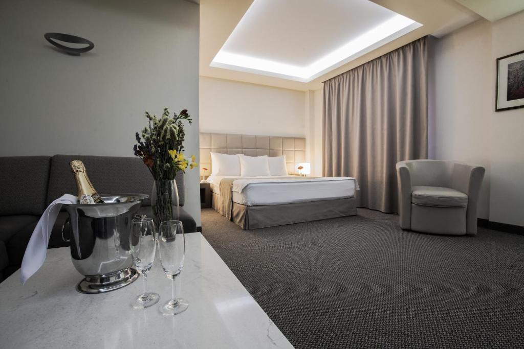 ein Hotelzimmer mit einem Bett und einem Tisch mit Weingläsern in der Unterkunft Aviatrans Hotel in Yerevan
