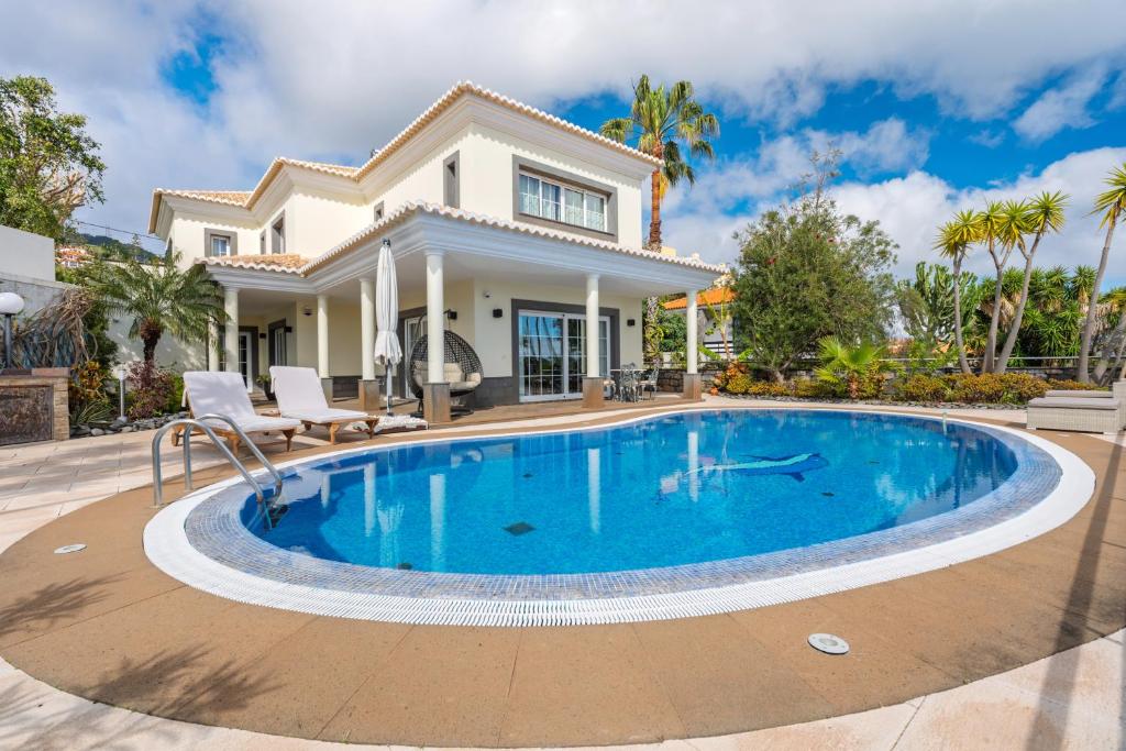 a villa with a swimming pool in front of a house at Villa Minimalista in Caniço