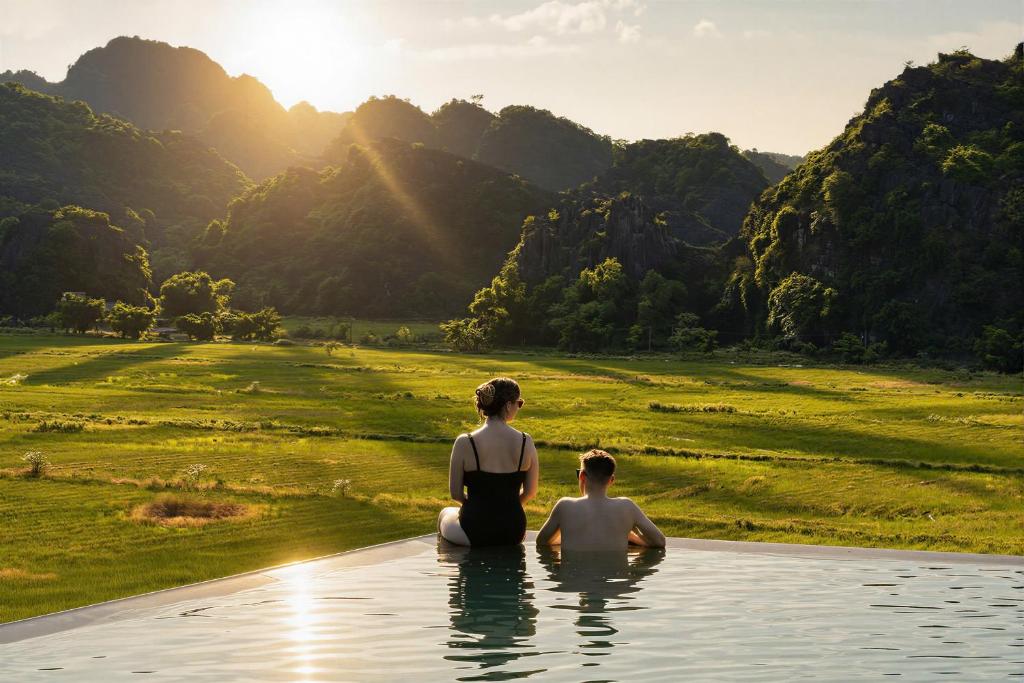 a man and a woman sitting in a pool of water at Hotel LaVue Tam Coc in Ninh Binh