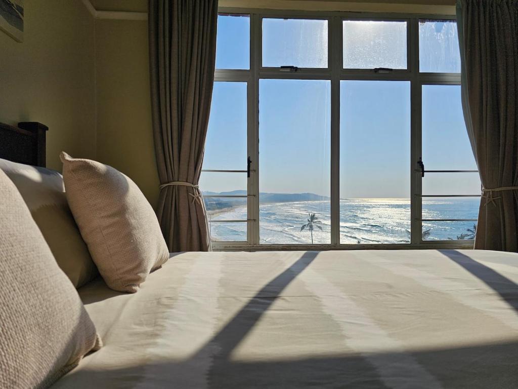 a bedroom with a bed and a large window at On The Beach Scottburgh in Scottburgh