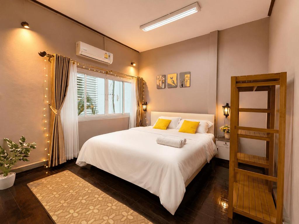 a bedroom with a large white bed with yellow pillows at Beyond Stay Thong Lor 11 in Bangkok