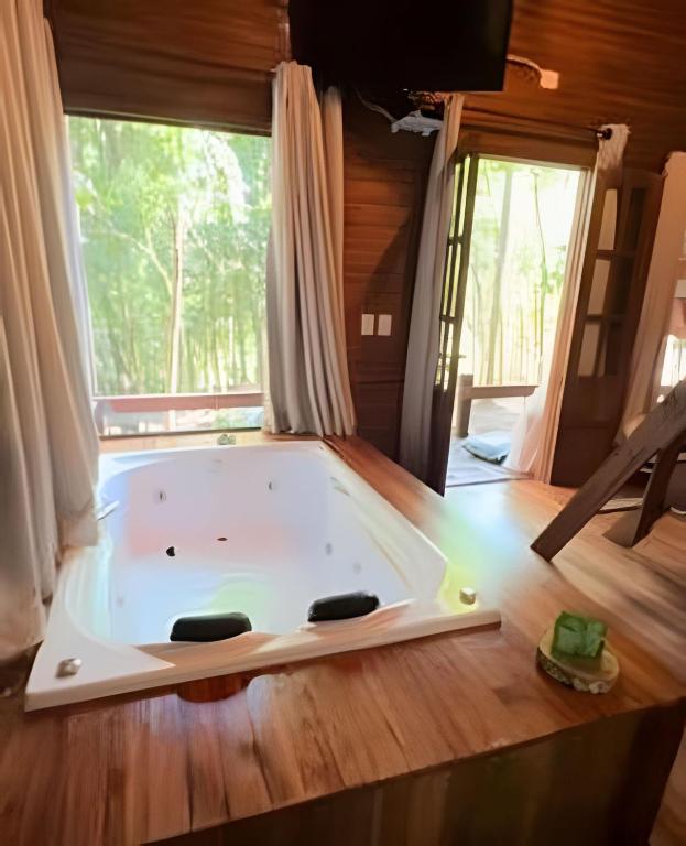 a bath tub in a room with a large window at Cabana Andorinha in Três Coroas