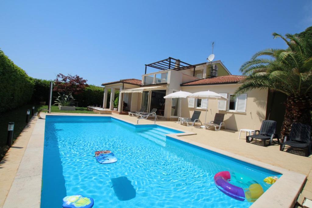a swimming pool in front of a house at Elegant Villa Hariz near Poreč - Fully AC & Large Pool in Gedići