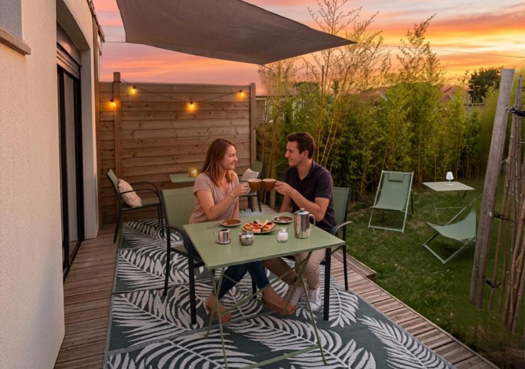 a man and woman sitting at a table on a patio at Bambou Zen Room in Rang-du-Fliers