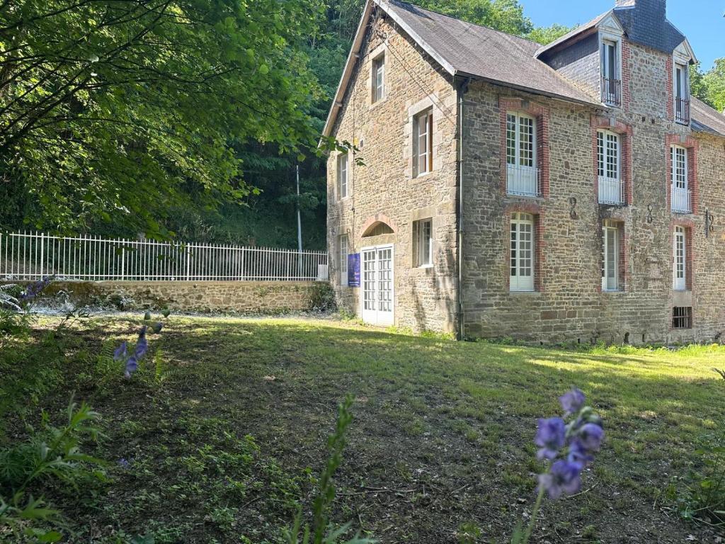 an old brick house with purple flowers in a yard at Manoir du Moulin Fleury in Villedieu-les-Poêles