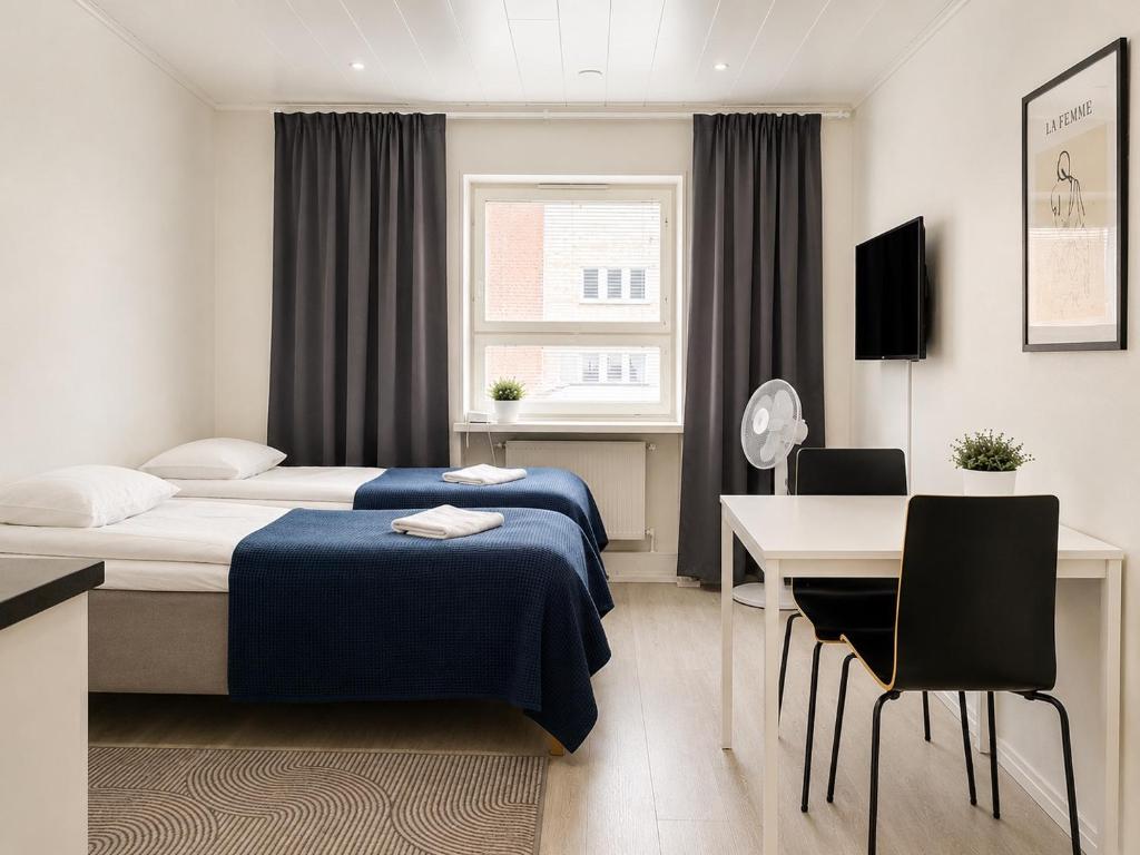 a hotel room with two beds and a desk at City Center Studio Pori in Pori