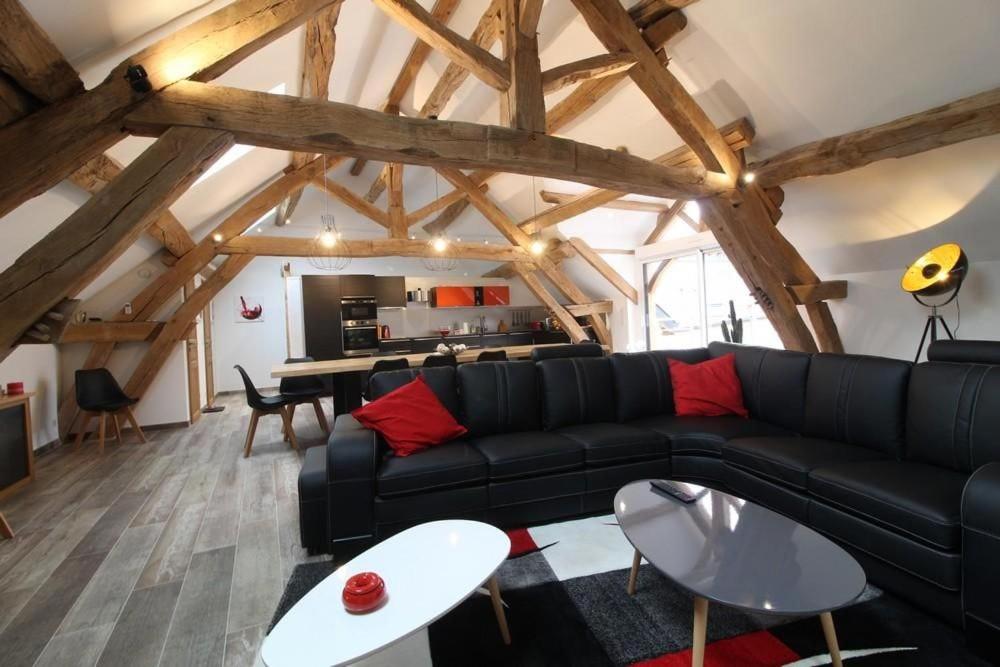 a living room with a black couch and a kitchen at Mise au Verre in Prémeaux