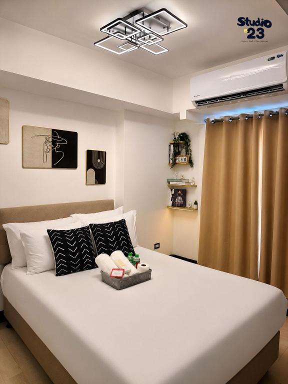 a bedroom with a large white bed with a television at Studio B23 Azure North in San Fernando