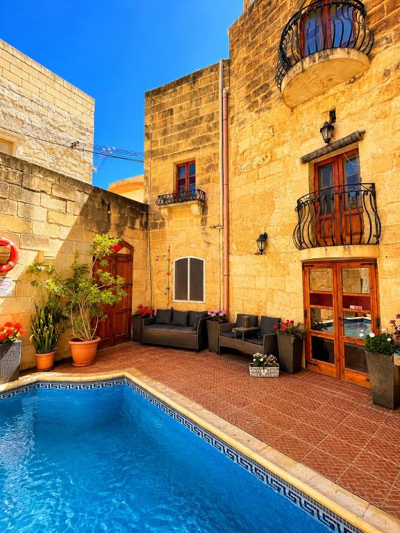 a swimming pool in front of a brick building at Kercem Boutique Farmhouse in Kerċem