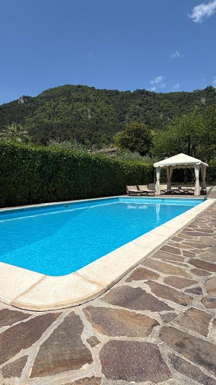 a blue swimming pool with a gazebo next to a mountain at Villa Oleandri pool with view-BGL in Salò