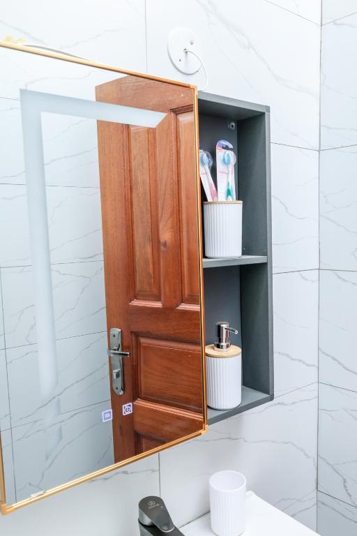 a bathroom mirror with a wooden door over a sink at Ruts Golden Homes in Kampala