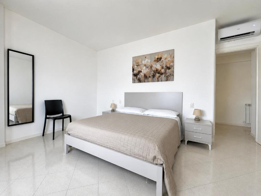 a white bedroom with a bed and a chair at Emy Dreams in Citta' Sant'Angelo