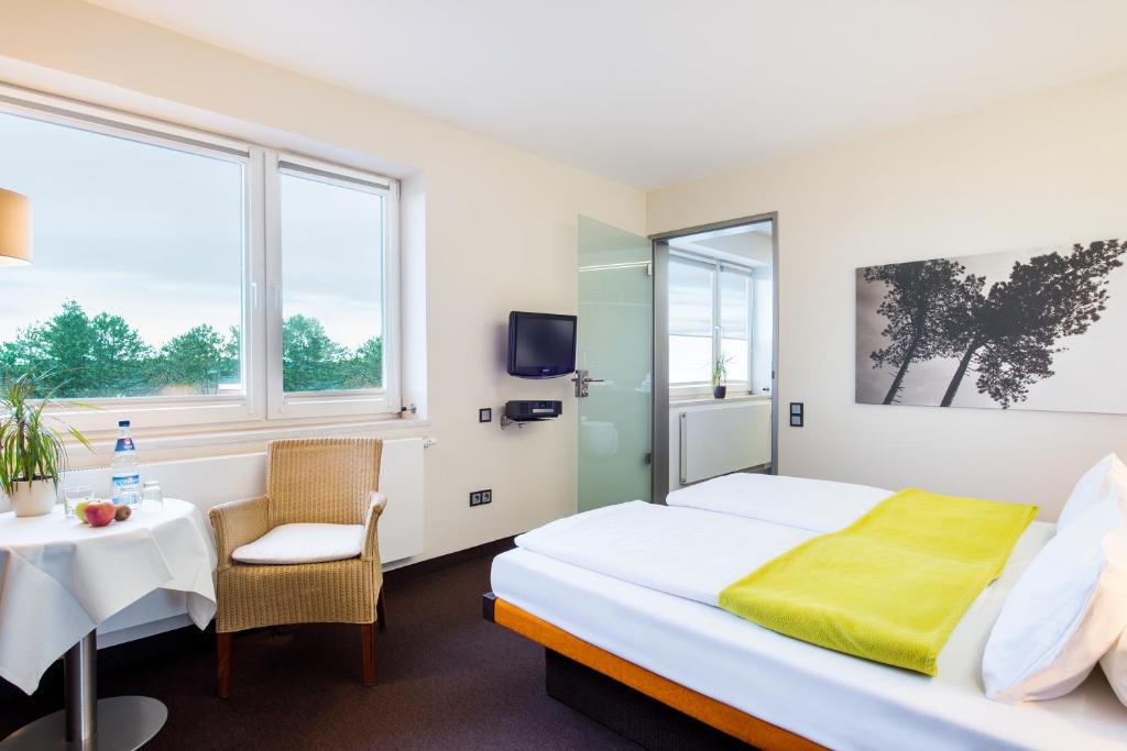 a hotel room with a bed and a table and chairs at Hotel Windschur in Sankt Peter-Ording