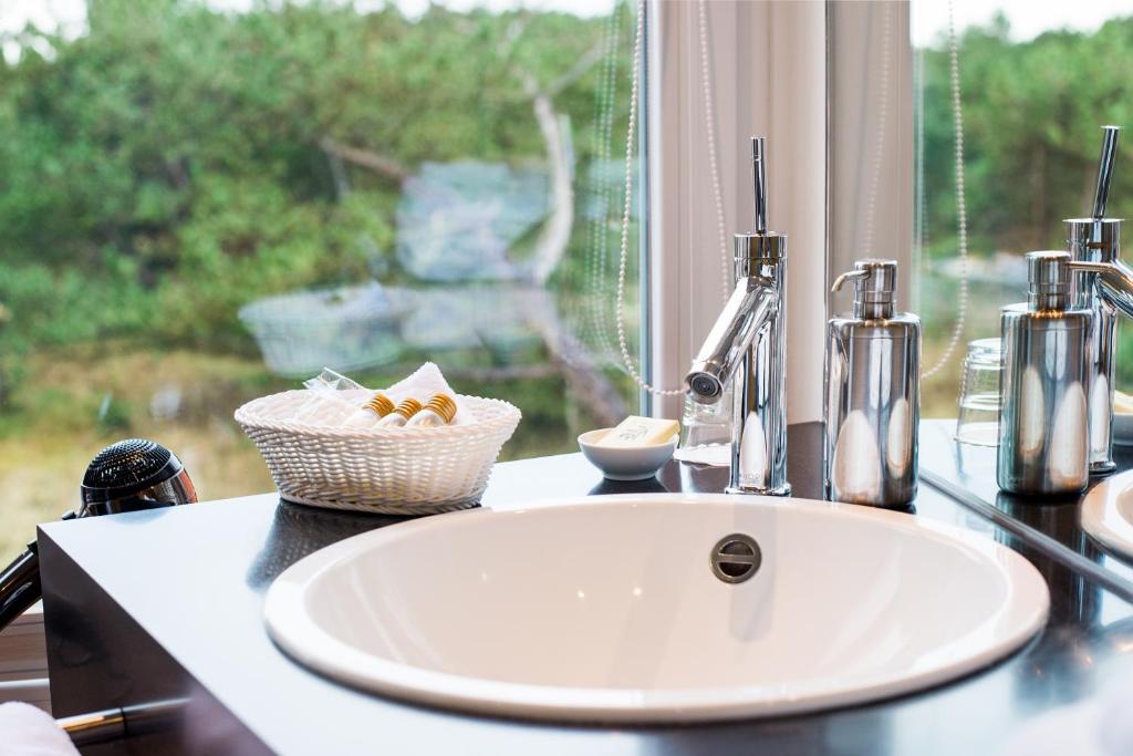 a bathroom counter with a sink and a window at Hotel Windschur in Sankt Peter-Ording