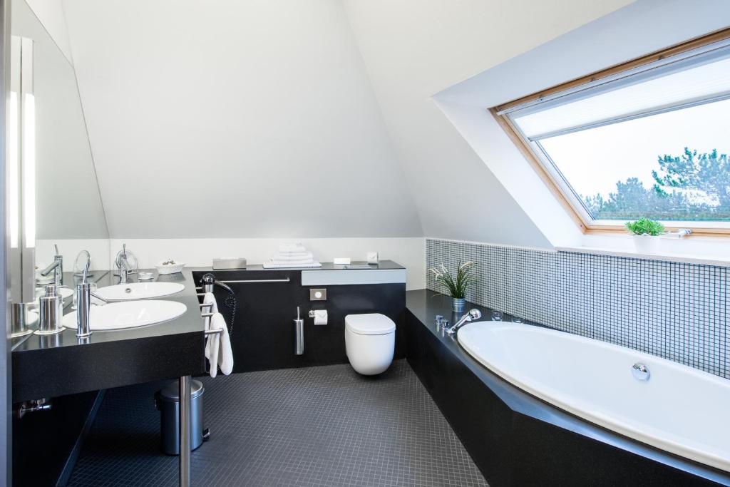 a bathroom with a tub and a toilet and a window at Hotel Windschur in Sankt Peter-Ording