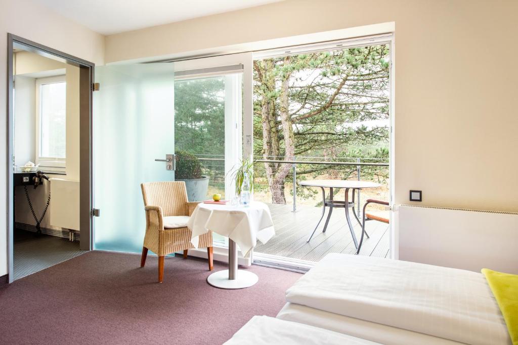 a bedroom with a bed and a table and a balcony at Hotel Windschur in Sankt Peter-Ording