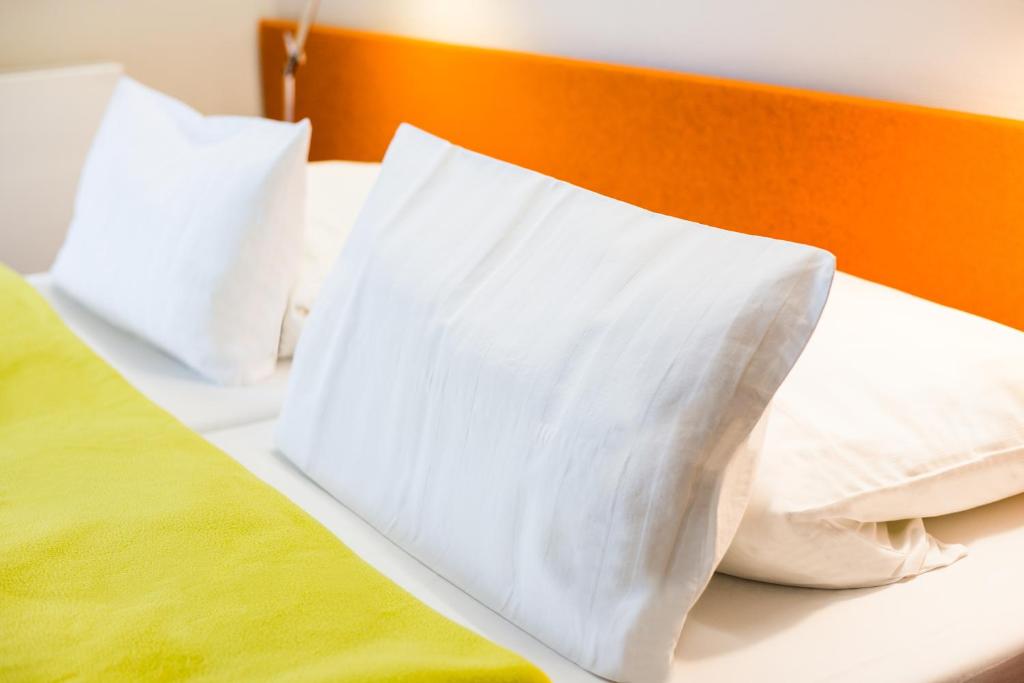 a bed with white pillows on top of it at Hotel Windschur in Sankt Peter-Ording