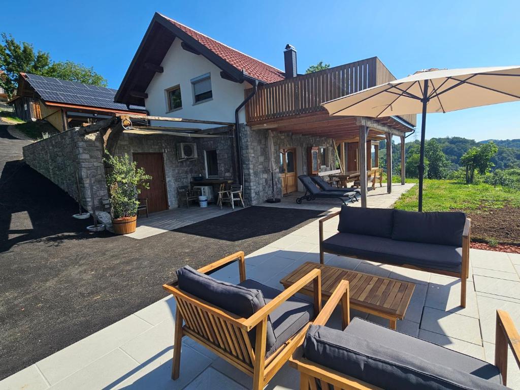 a patio with chairs and a couch and an umbrella at Pirman Vineyard Cottage in Bučka