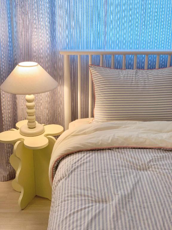 a bedroom with a bed and a lamp on a table at stay mongle in Suwon