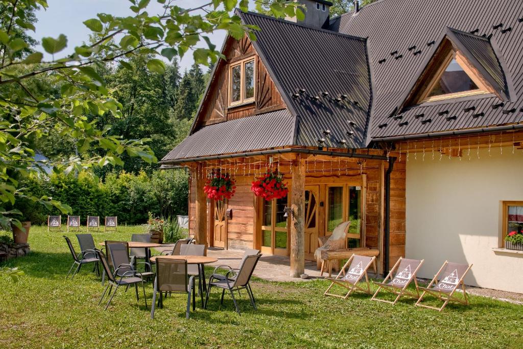 a house with a table and chairs in the yard at GLICZAROWA OSADA, Chata 18 osób, Domek 8 osób NA WYŁĄCZNOŚĆ, 8 sypialni z łazienkami, spokój, przyroda, wyjątkowe miejsce in Gliczarów