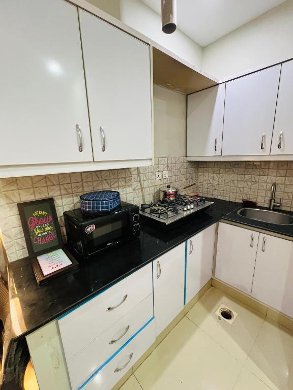 a kitchen with white cabinets and a black counter top at Royal Stays 2Bed Cozy Apartment in Multan