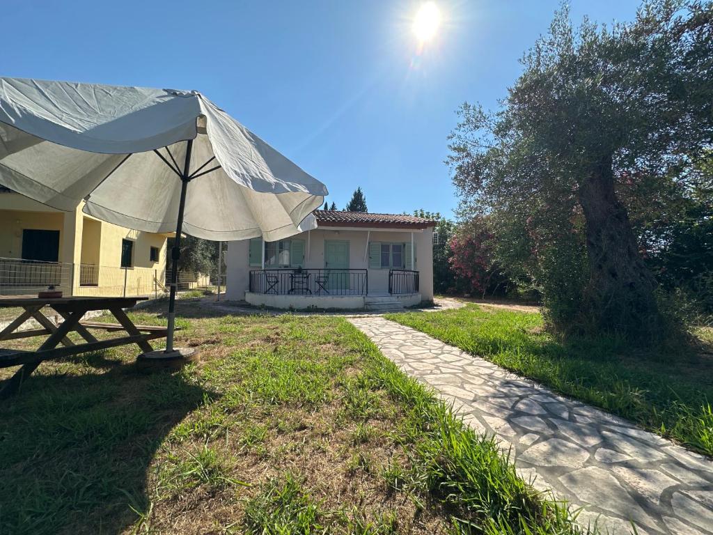 a house with a table and an umbrella in the yard at Olive terra holiday aparments in Lefkimmi