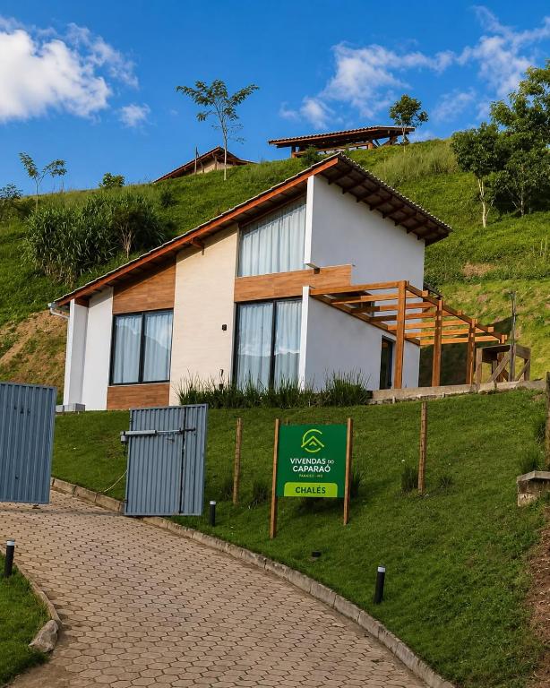 a house on a hill with a sign in front at Chalé 1 - Vivendas do Caparaó in Pedra Menina