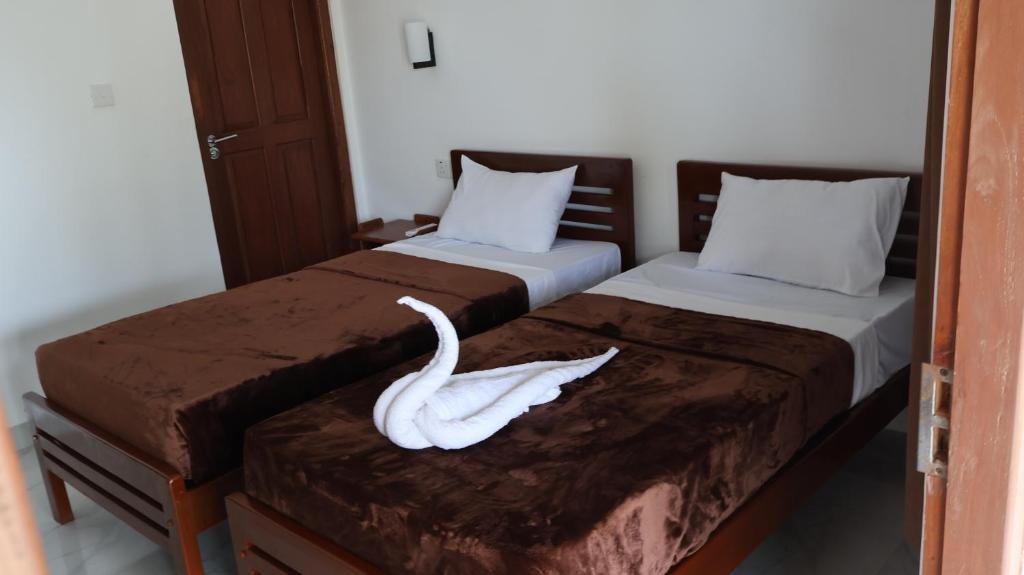 a swan decoration on two beds in a room at Adam's Palm Resort in Talaimannar