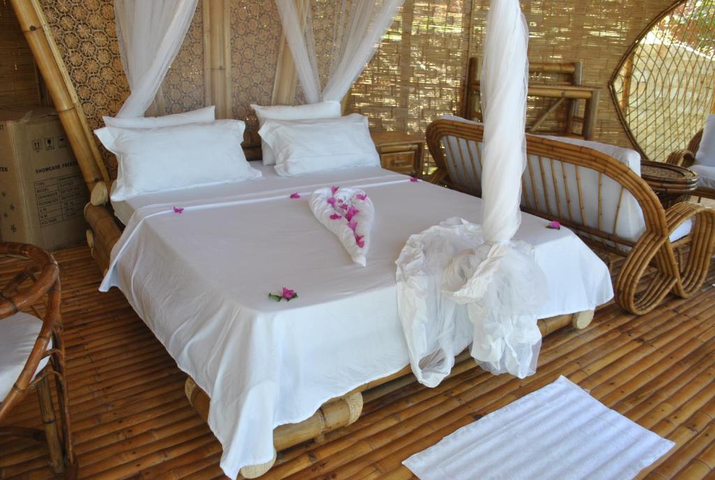 a bedroom with two beds with white sheets and pillows at Le Caveau de lemuriens in Nosy Be