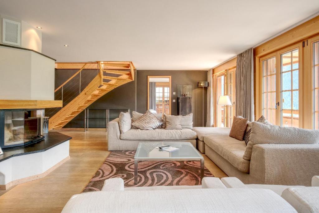 a living room with two couches and a staircase at Apartment Bränderli - GRIWA RENT AG in Grindelwald