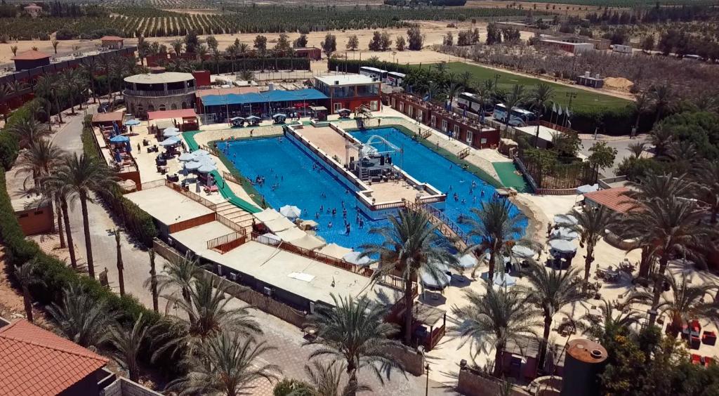 an aerial view of a resort pool with palm trees at Kemzo Hotel in Abū Rawwāsh