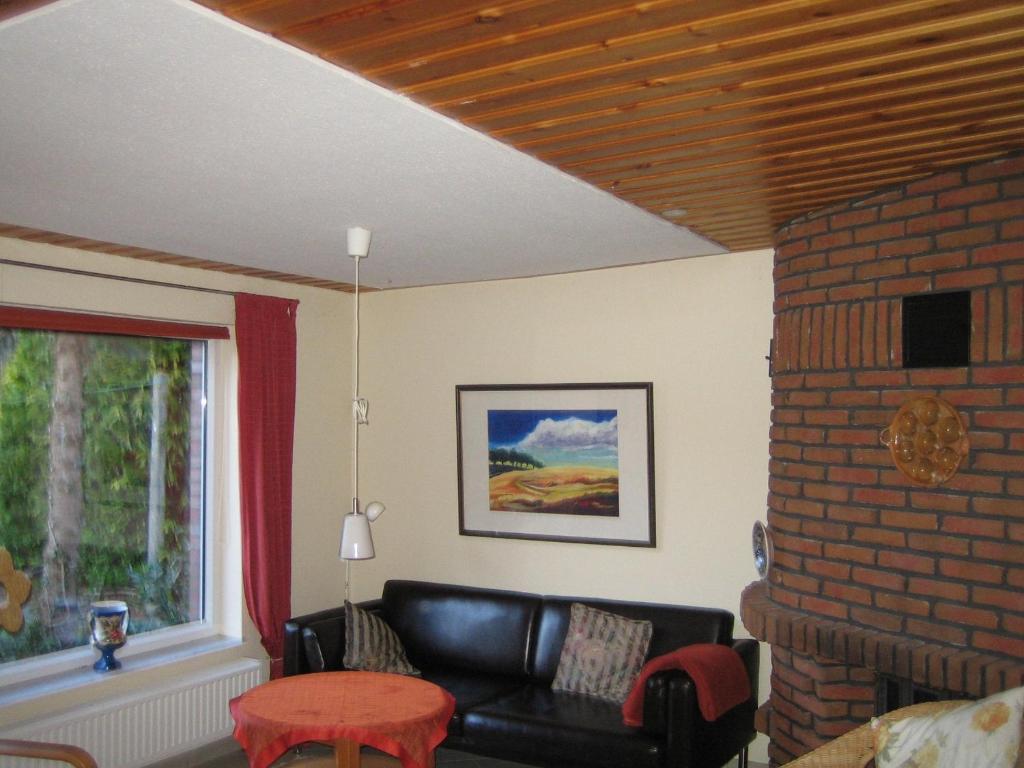 a living room with a black leather couch and a window at Kajüte H-8 in Butjadingen