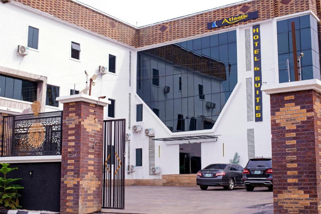 a building with a gate and a car parked in a parking lot at Indian Atlantic Hotel & Suites in Agbor