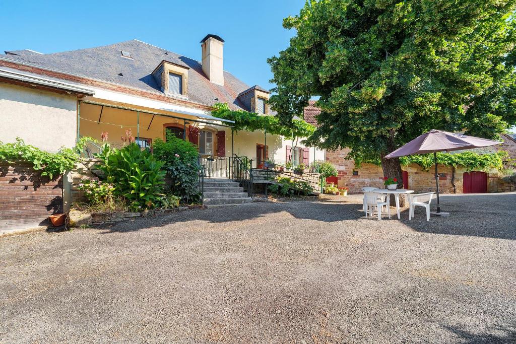 a house with a table and an umbrella in front of it at Maison De Campagne in Ligneyrac